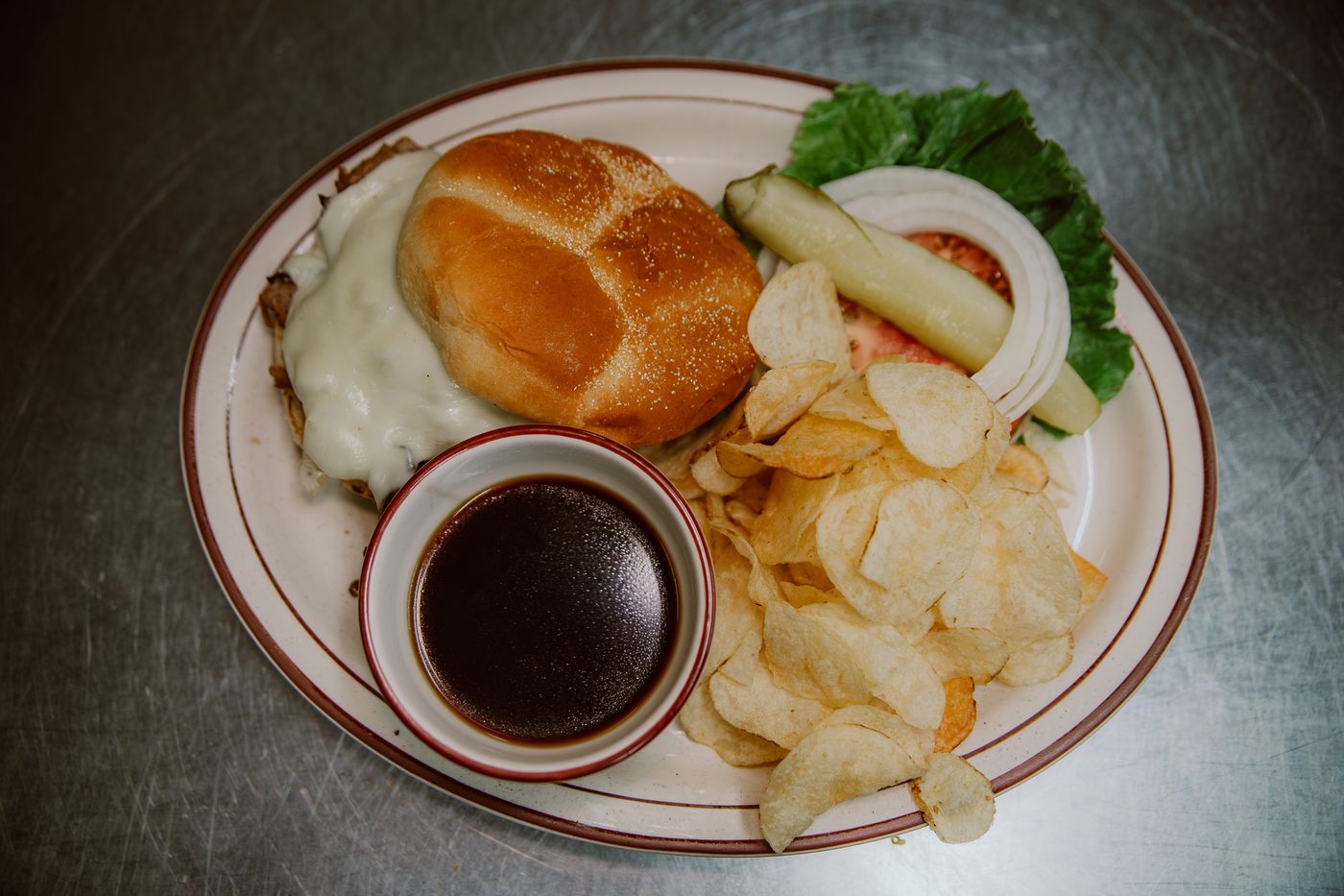 Prime rib sandwich with melted mozzarella, au jus and chips